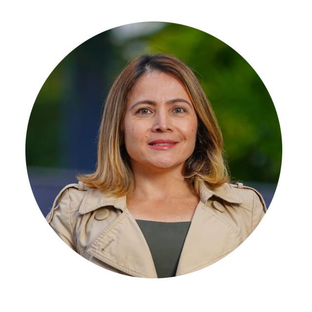 Foto de Marinalva, mulher branca de cabelo entre castanho claro e loiro na altura do ombro, olhos claro. Ela está de sobretudo bege e blusa verde e sorri.